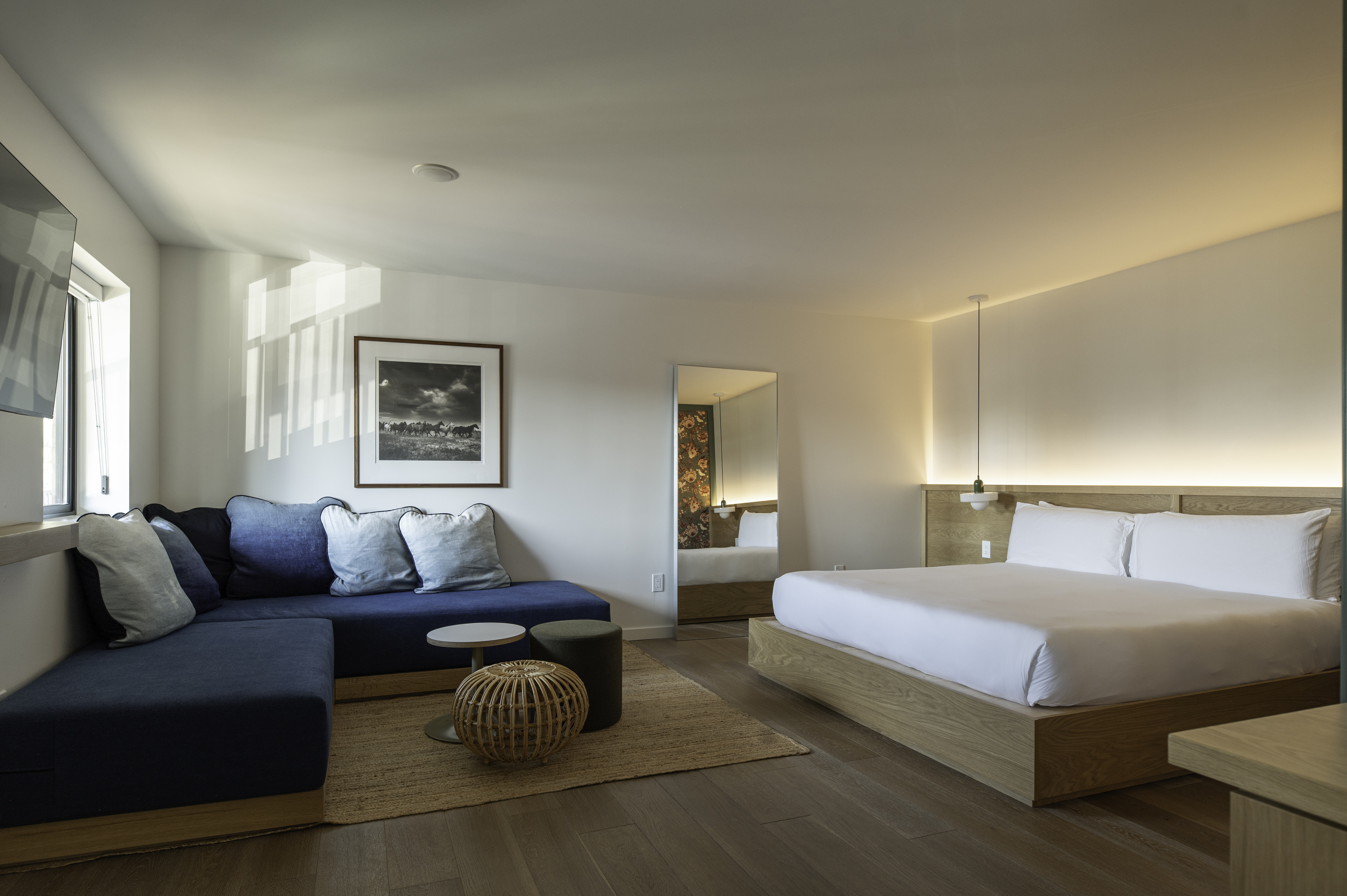 A wide view of a hotel room with a blue sectional sofa, king-sized bed, and modern decor.